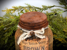 Load image into Gallery viewer, A rustic jar with a rusty lid, is surrounded by greenery. The jar is tied with a piece of tattered cheesecloth, adding a vintage feel to the scene.